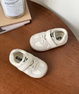 Detailed top-down view of cream soft-sole toddler sneakers on wooden table