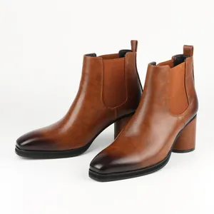 Detailed view of brown leather Chelsea boots with chunky high heels and burnished toes