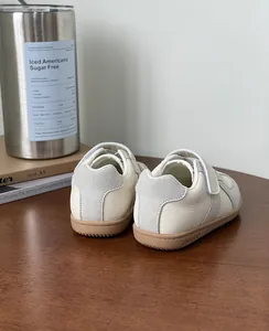 Rear view detail of off-white cream toddler sneakers with soft tan non-slip rubber soles