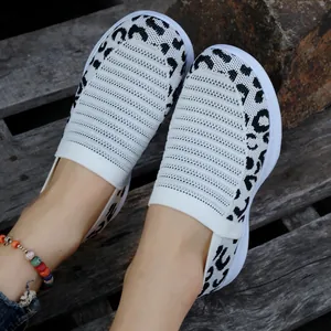 Detailansicht von weißen Strick-Slip-On-Sneakern mit Leopardenmuster auf Holzsteg