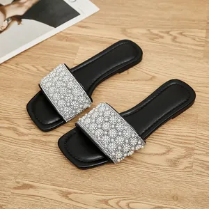 Top view detail of women's square-toe flat slides with pearl and rhinestone decor.