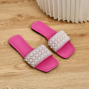 Close-up of pearl and rhinestone embellishments on fuchsia square-toe flat slides