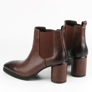Close-up rear view of brown Chelsea boots with high block heels and elastic panels.