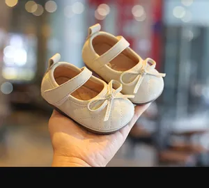 Nahaufnahme von beigen gesteppten Baby-Mary-Janes mit Schleife und weicher Sohle