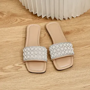 Detail view of pearl and rhinestone floral embellishments on square-toe flat sandals.