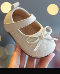 Nahaufnahme eines cremefarbenen Baby-Mädchen-Schuhs mit Schleife und Steppmuster-Detail