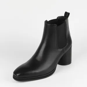 Side view of sleek black Chelsea boots with high block heel and elastic side panel.