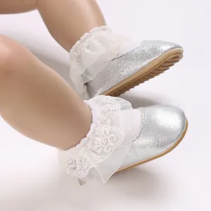 Close-up of silver glitter baby shoes with white lace ruffle details on a doll model