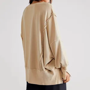 Detail van een ruimvallend beige sweatshirt met verlaagde schouders en zichtbare naden.