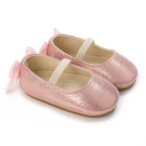 Close-up of sparkling pink glitter baby shoes featuring ribbon bows and elastic straps