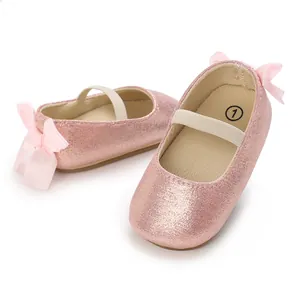 Close-up of pink glitter baby Mary Jane shoes with ribbon bows and elastic straps