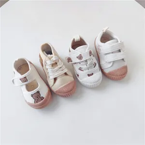 Macro view of various toddler canvas shoes featuring cute cartoon bear patterns and soft soles.