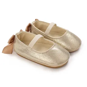 Macro view of sparkly gold baby Mary Jane shoes featuring back bow and elastic strap