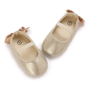 Detailed view of champagne gold glitter baby ballet flats with silk bows and elastic straps