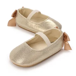 Detailed view of shimmering champagne gold baby girl shoes featuring a cute bow and elastic strap