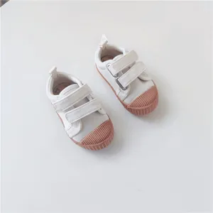 Top view of baby canvas shoes with soft soles, pink rubber caps, and bear detail