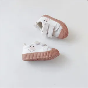Close-up detail of white children's canvas shoes with cute bear pattern and soft sole