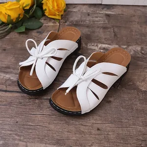 Macro view of white women's wedge sandals featuring decorative bow and cutout design