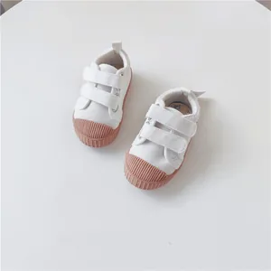 Close-up of white children's canvas shoes with brown ribbed rubber toes and velcro straps