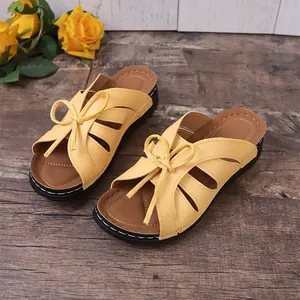 Detailed view of yellow wedge sandals with decorative bow and open toe design.