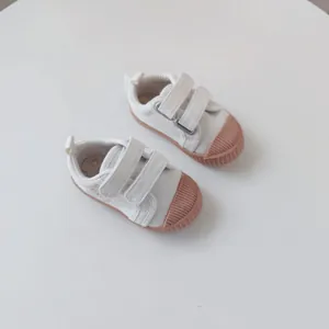 Close-up of white baby canvas shoes with pink soft soles and cute bear design
