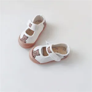 Detail view of white baby canvas shoes featuring cute cartoon bear print and soft soles