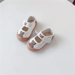 Detailed view of white baby canvas shoes with a cute bear print and soft soles