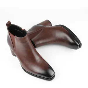 Close-up detail of brown leather Chelsea boots with burnished toe and high heel