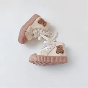 Close-up view of cute baby canvas shoes featuring a teddy bear patch and soft pink rubber sole