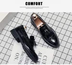 Vue macro de mocassins Brogue en cuir verni noir avec glands et gravures complexes