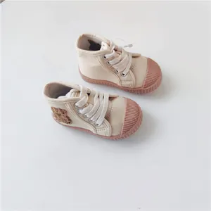 Detailed view of cream toddler canvas shoes with cute bear applique and soft pink soles.