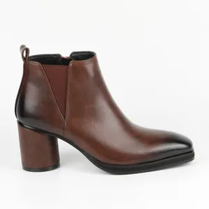 Side view of brown leather Chelsea boots with block heel and burnished square toe.