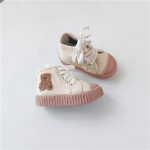 Detailed view of cream toddler canvas shoes featuring a cute teddy bear patch