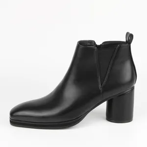 Side view detail of a classic black faux leather Chelsea boot featuring a stylish block heel