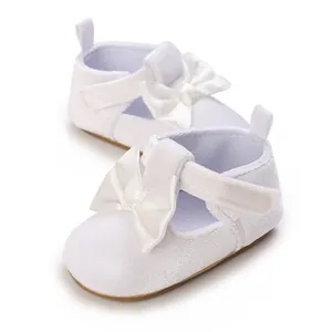 Detailed view of white soft sole baby shoes featuring an elegant satin bow accent.