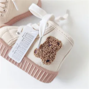 Detailed view of cream baby canvas shoe featuring bear embroidery and Japanese size tag