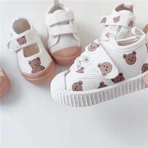 Detailed view of children's canvas shoes with cute teddy bear pattern and soft soles