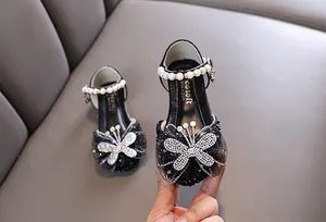 Detailaufnahme von Mädchenschuhen in Schwarz mit glitzerndem Schmetterling und Perlenriemen