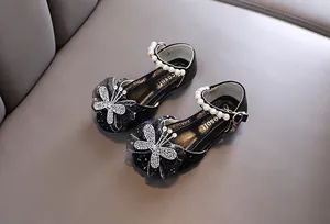Detail der schwarzen Glitzer-Prinzessinenschuhe mit Strass-Schmetterling und Perlenriemen