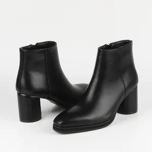 Detailed view of elegant black leather ankle boots with high block heels and side zipper.