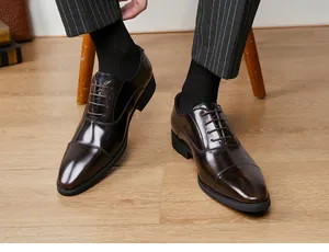 Close-up of polished dark brown cap-toe genuine leather oxford shoes worn by a male model