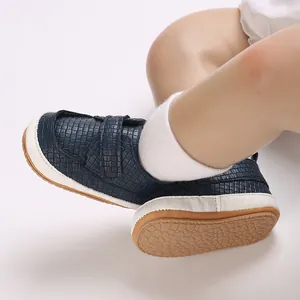 Dettaglio della scarpa neonato intrecciata blu navy con suola marrone antiscivolo