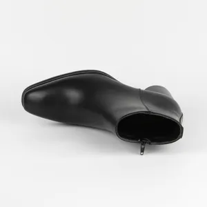Close-up detail of men's black leather Chelsea boot showing side zipper and smooth texture