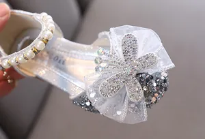 Nahaufnahme der glitzernden Strassschleife und des eleganten Perlenriemens an Prinzessinnenschuhen