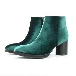 Detailed side view of elegant emerald green velvet ankle boots with chunky black heels