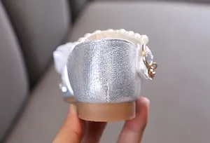 Nahaufnahme der silbernen glitzernden Mädchen-Prinzessin-Schuhferse mit Perlenband