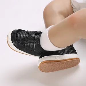 Primo piano di scarpine per neonati intrecciate nere con suola morbida e velcro.