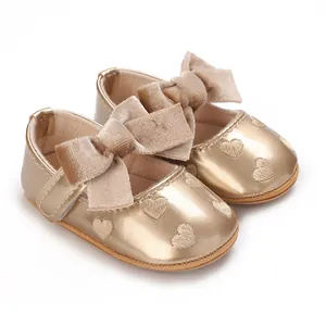 Dettaglio di scarpe neonata dorate con grandi fiocchi di velluto e ricami a cuore
