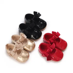 Vista dettagliata delle scarpe da principessa per neonata con fiocco in nero, oro e rosso