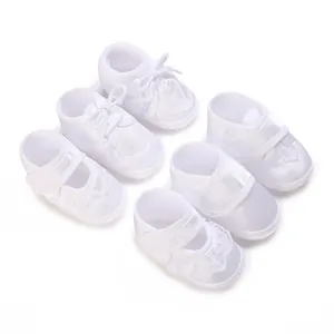 Detailed view of various white soft-sole baby christening shoes with elegant embroidery